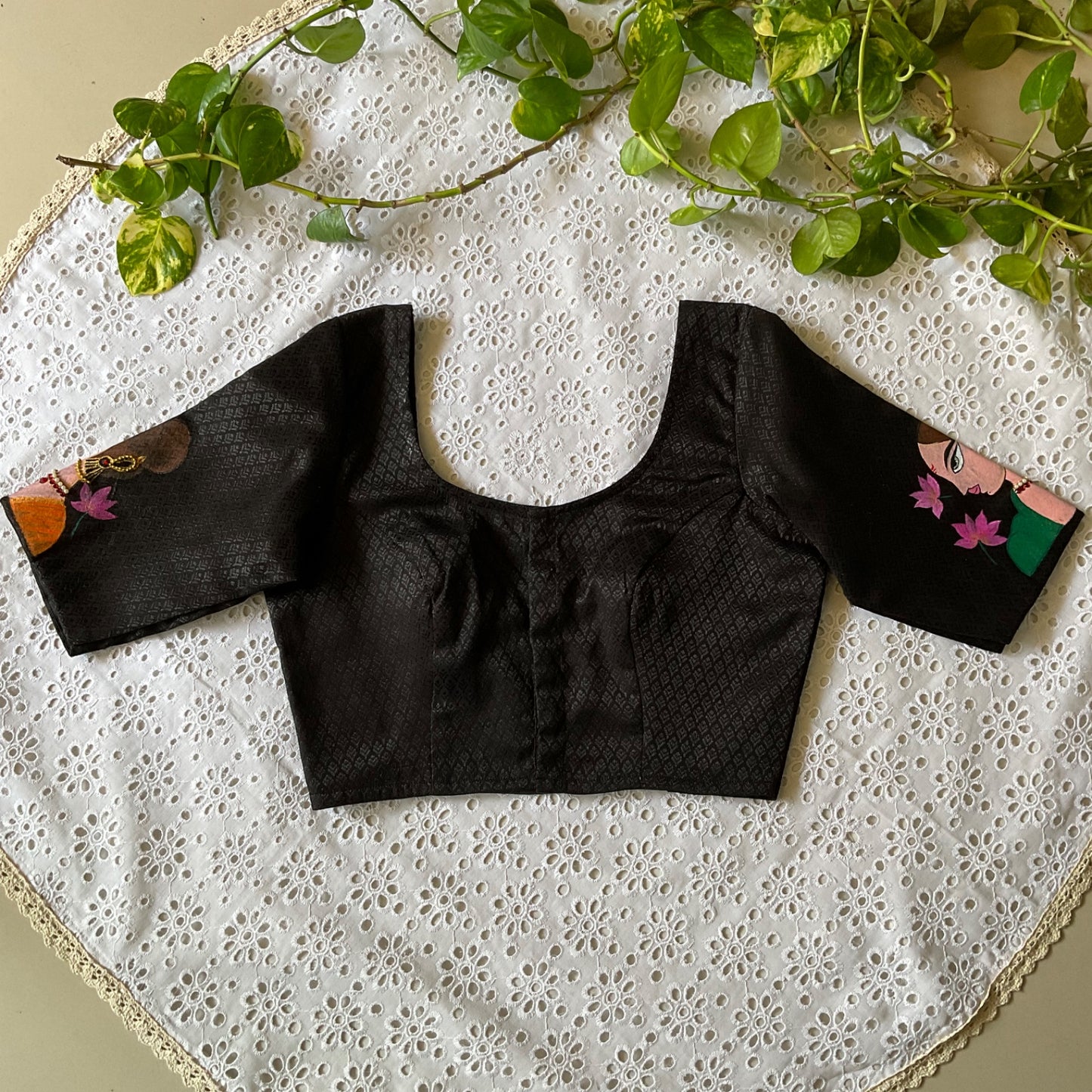 Black blouse with floral sleeves on a white lace fabric background