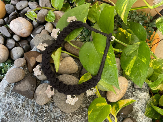 Black braided hair tie on a bed of stones and leaves