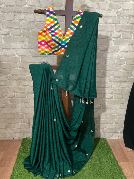 Green saree with a colorful blouse on a wooden stand against a brick wall.