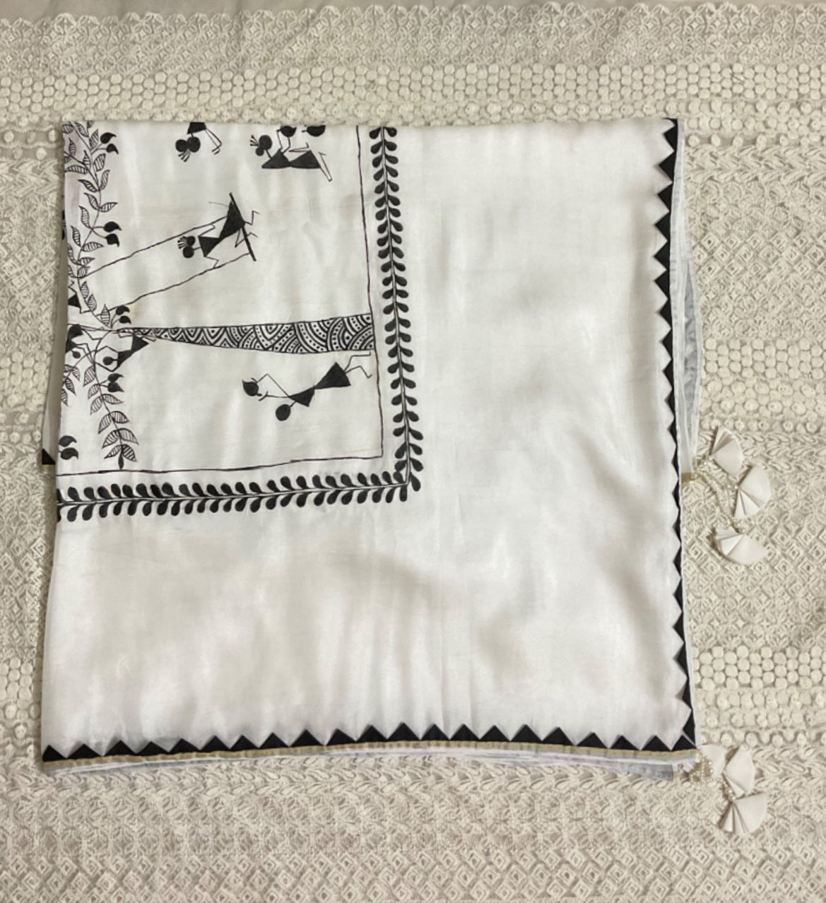 White saree with black embroidery on a textured beige background