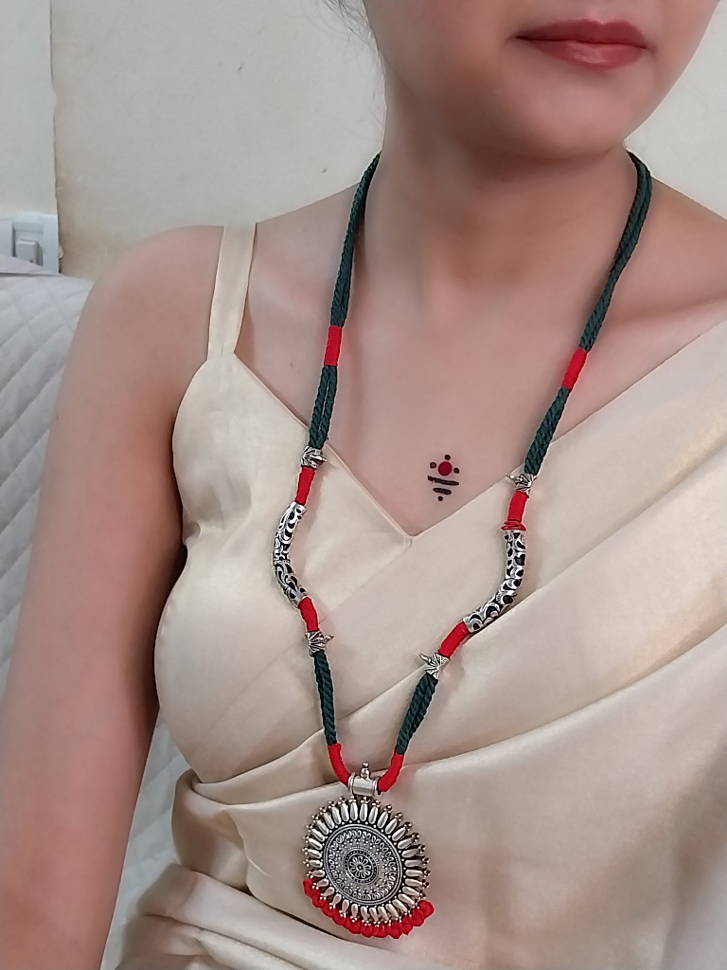 green necklace with oxidized silver pendent and red accents