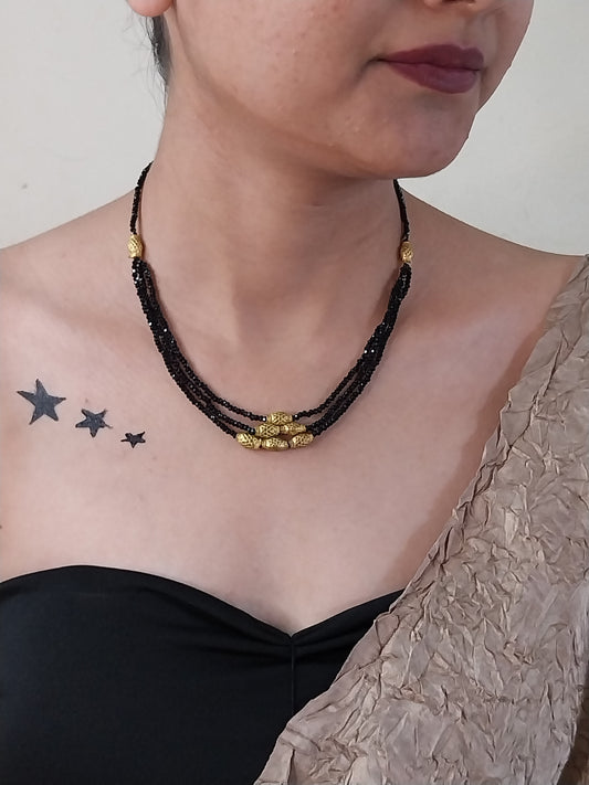 Person with star tattoos on shoulder and black beaded necklace