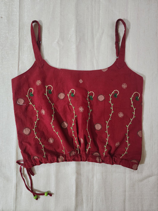 Red embroidered top on a light wooden surface