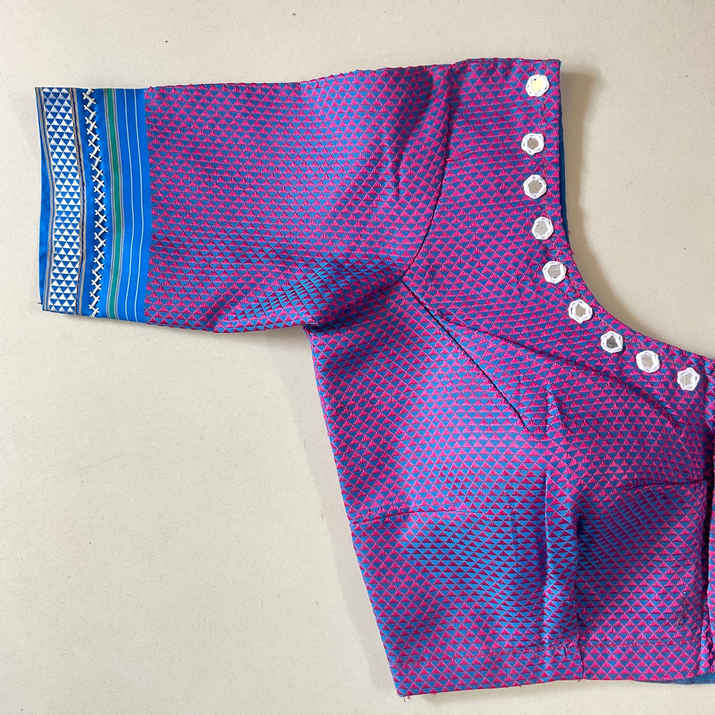 Purple and blue patterned blouse with decorative glasses on a beige background