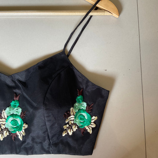 Black top with floral embroidery on a beige surface