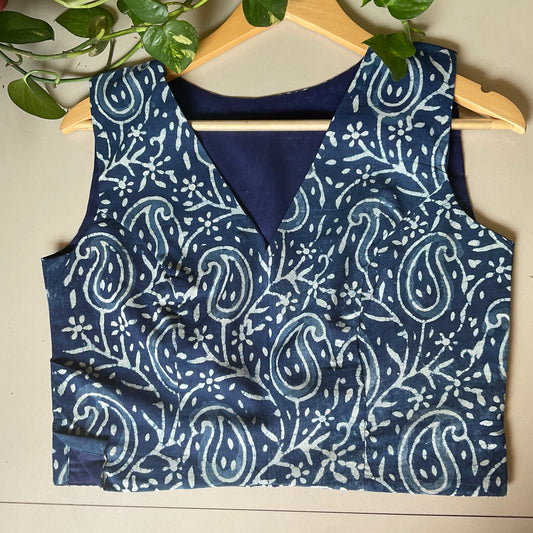 Indigo blouse with white paisley pattern on a wooden hanger against a neutral background.