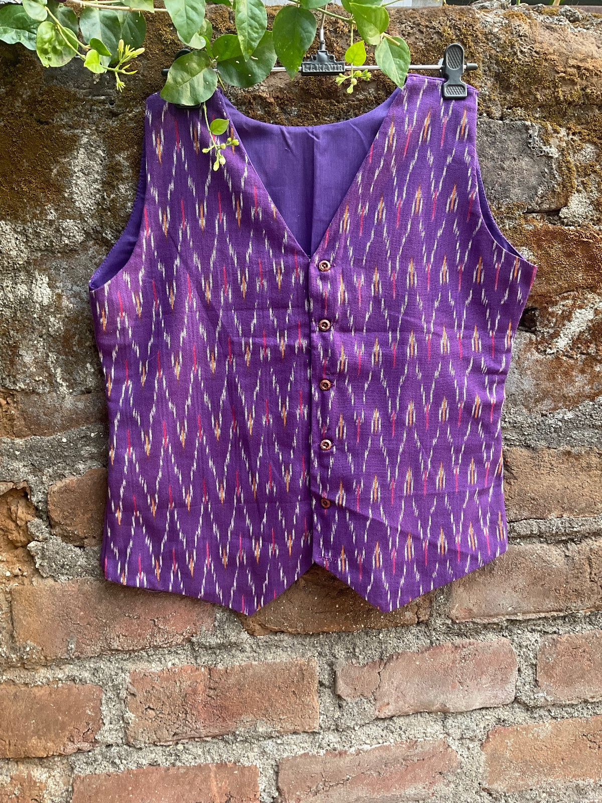 Purple patterned garment on a stone wall with greenery