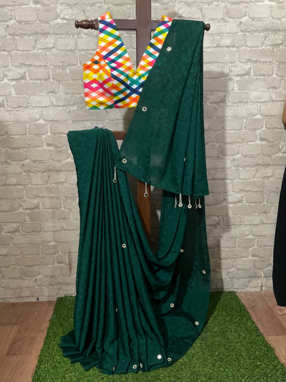 Green saree with a colorful blouse on a wooden stand against a stone wall.
