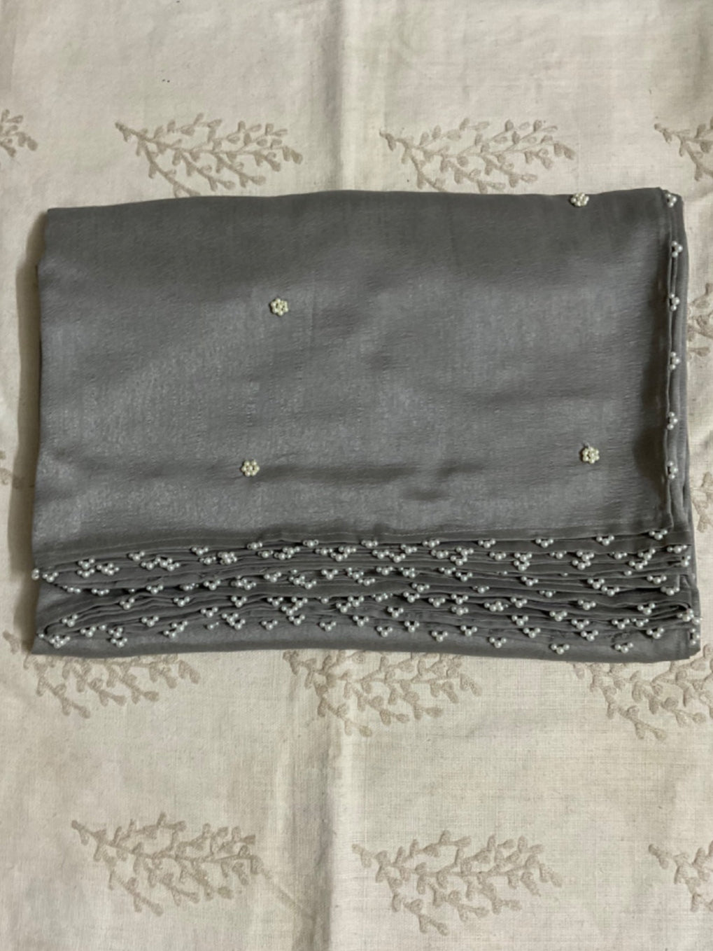 Grey saree with floral motifs on a white fabric background