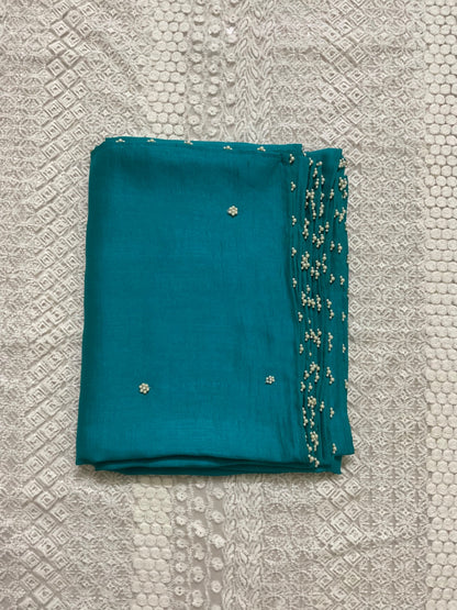 Teal saree with floral embroidery on a textured grey background
