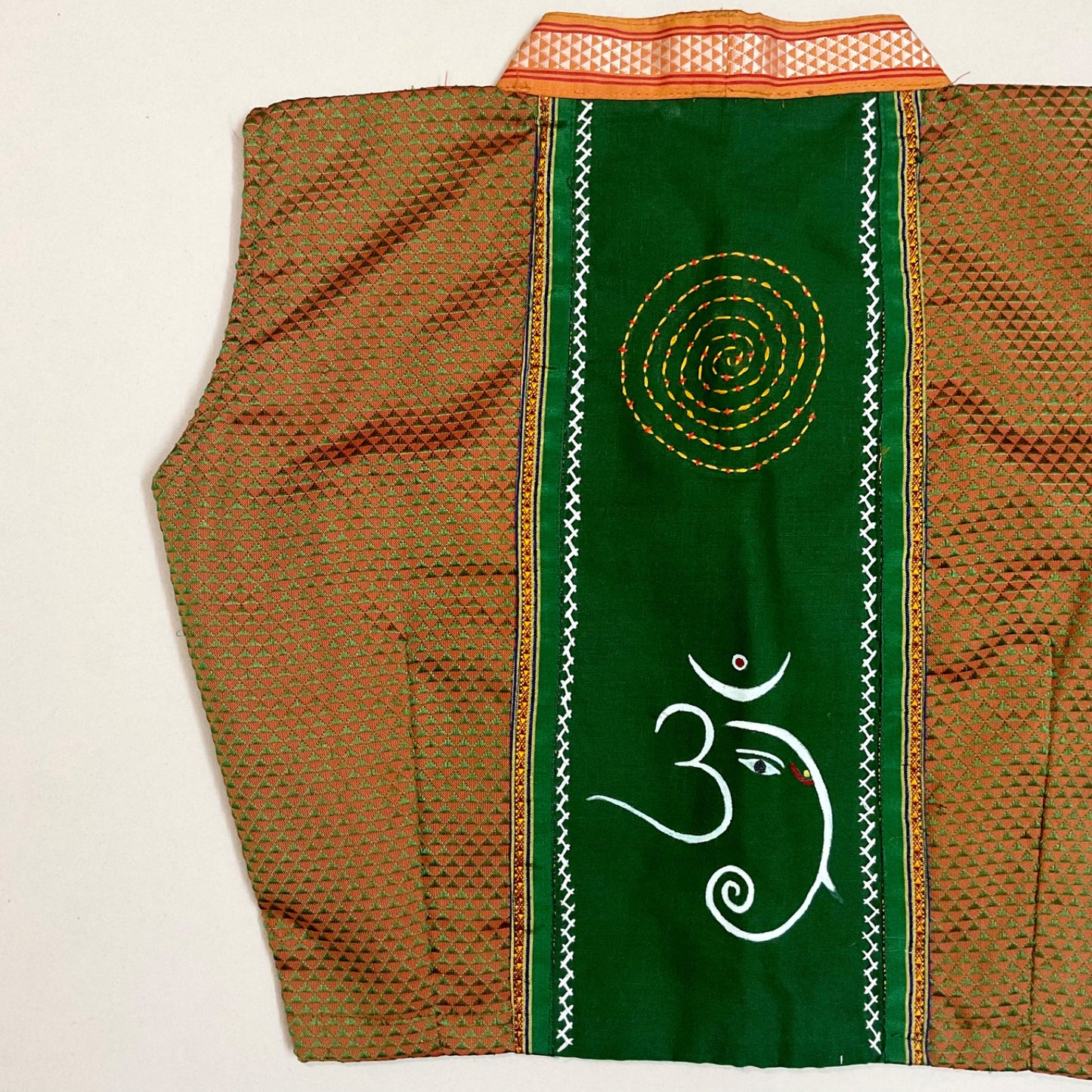 Traditional garment with green panel featuring a symbol on a beige background