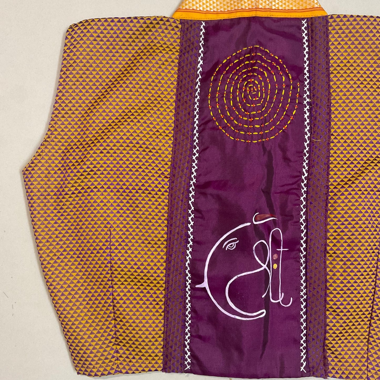 blouse with a yellow geometric pattern and a purple section with a white design on a beige background