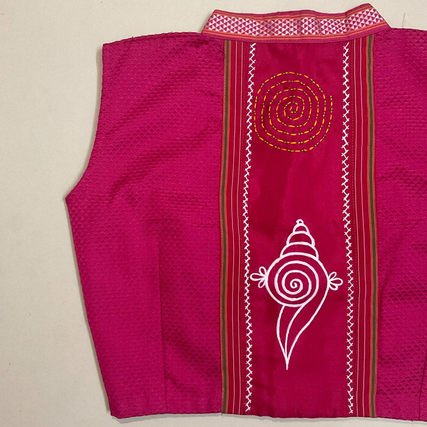 Pink garment with white and gold embroidery on a beige background