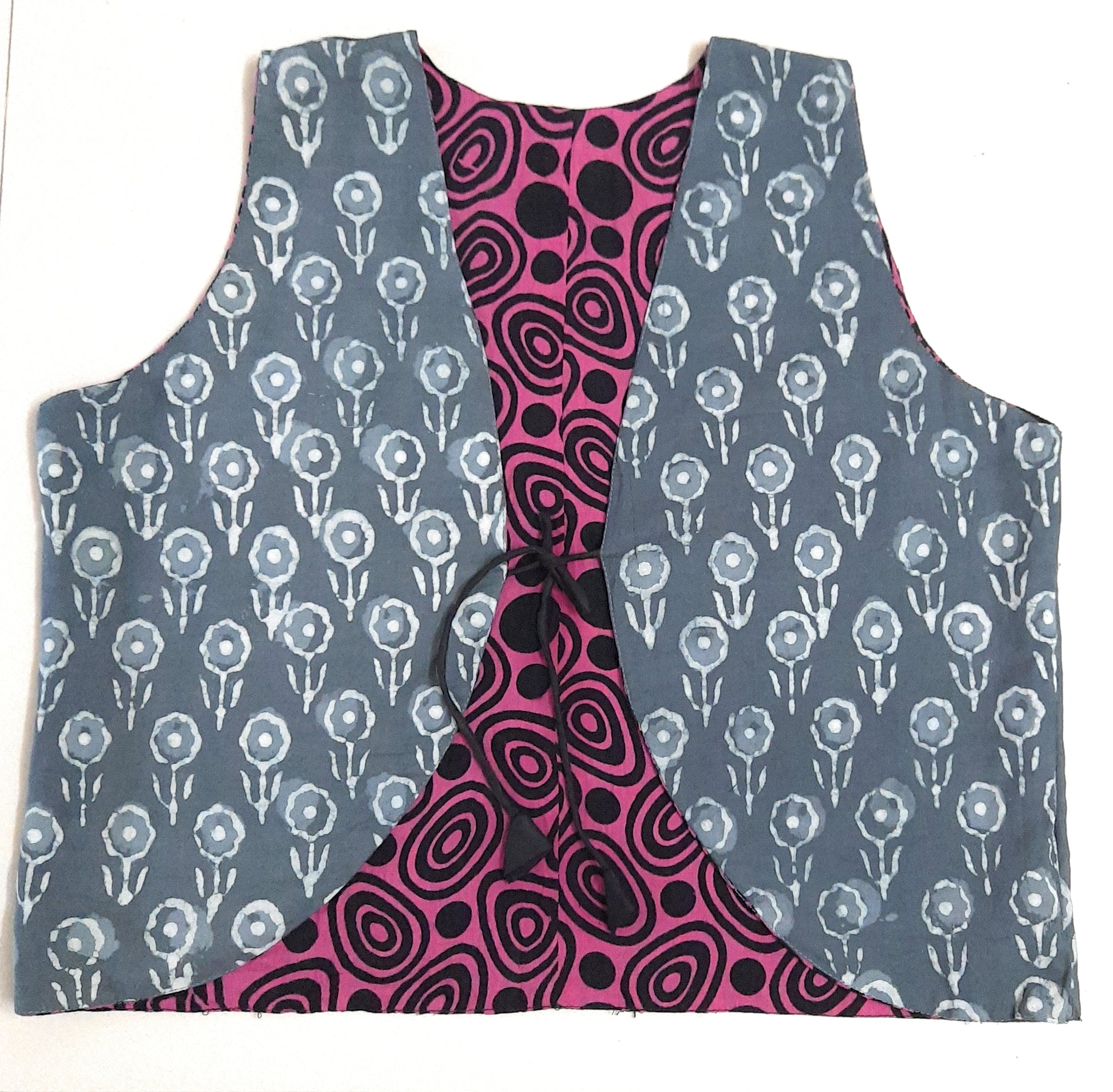Two-sided patterned vests, one with a grey floral design and the other with a pink and black abstract design, on a white background.