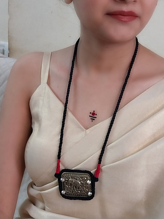 Person wearing a necklace with a decorative pendant