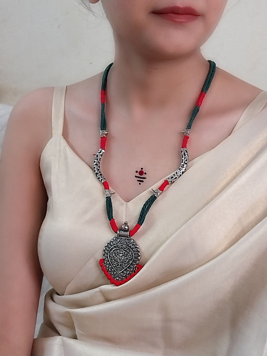 green necklace with oxidized silver pendent and red accents
