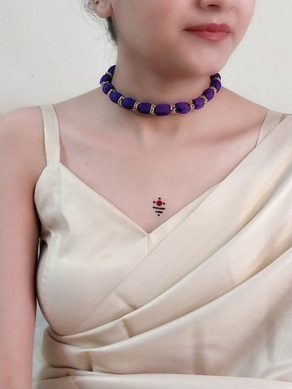 Person wearing a purple beaded choker and a beige saree.